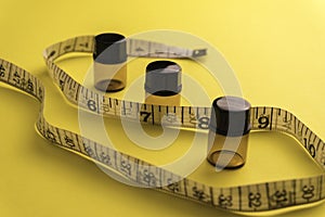 Empty bottle with a measuring tape, diet or healthy eating concept, Yellow background with soft focus