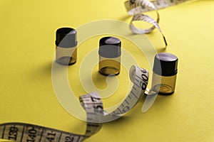 Empty bottle with a measuring tape, diet or healthy eating concept, Yellow background with soft focus