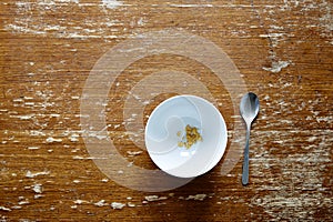 Empty bowl with little cereal on dark wooden table