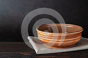 Empty bowl plate on wooden table over dark brown background