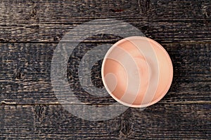 Empty bowl of white clay on an old wooden table surface