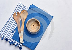 Empty bowl and wooden spoons on a white table, top view