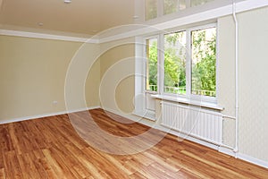 Empty bright room with a wooden floor and light wallpaper. The apartment is after renovation.