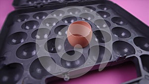 Empty broken egg shell in grey tray on pink background