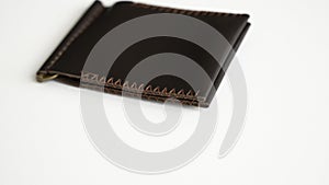 Empty brown men's money clip handmade leather wallet with a two pockets for cards lies on a white table. Selective