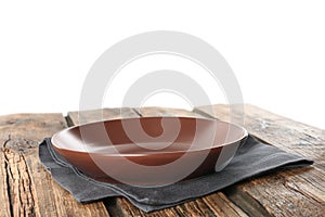 Empty brown plate and napkin on table against white background