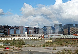 empty brownfield site in leeds england with weeds growing through concrete and a burned out abandoned car surrounded by