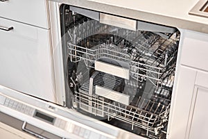Empty Built-in dishwashers with opened door. Home appliance dishwasher machine in modern kitchen. White tone and clean