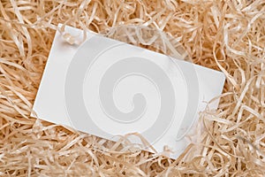 Empty business card as a placeholder for shipping text on raffia pile.