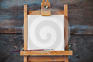 Empty canvas on easel on wooden background.