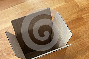 An empty cardboard box on a wooden floor