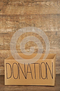 Empty cardboard donation box on brown background. Inscription donation
