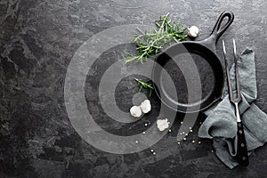 Empty cast iron frying pan on dark grey culinary background, view from above