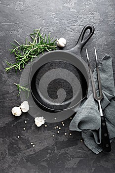 Empty cast iron frying pan on dark grey culinary background, view from above