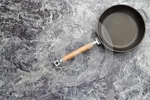 Empty cast iron frying pan on dark grey culinary background, view from above