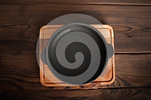 Empty cast iron round frying pan on textured wooden background close-up and copy space