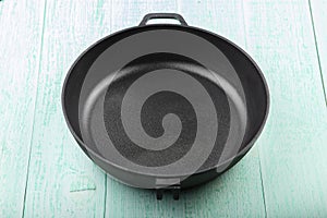 Empty cast iron skillet frying pan on wood background