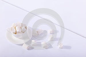 Empty ceramic cup with marshmallows on a saucer, on a white background. Hard shadow from the sun, the concept of morning