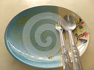 Empty ceramic dish with chicken tracery on the dish spoon and fork on top view. After meal