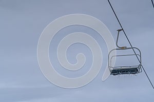 Empty chair lift with icicles against cloudy sky