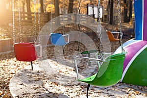 Empty chair multicolored colorful chain swing carousel at old vintage retro entertainment amusement park autumn sunset