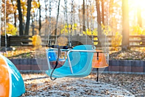 Empty chair multicolored colorful chain swing carousel at old vintage retro entertainment amusement park autumn sunset