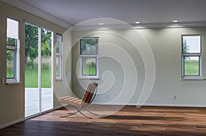 Empty Chair Sitting on the Floor Facing Glass Door in Empty Room of House with Blank Wall