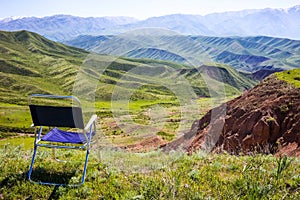 An empty chair stands on a clearing amidst magnificent mountains. Conceptual photo-nature without man