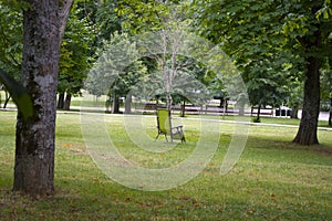 Empty chair stands on the grass in the park