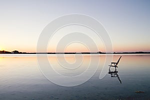 Empty chair in the water of a blue lake