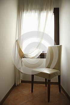 Empty chair by window with drapes.