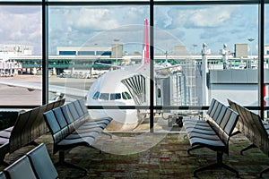 Empty chairs in the departure hall at airport with airplane parking. Travel and transportation in airport concepts