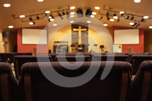 Empty chairs facing cross and worship stage in church