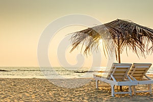 Empty chairs under thatched umbrellas on a sandy beach