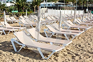 Empty chaise-lounges on the beach in the city of Costa Teguise