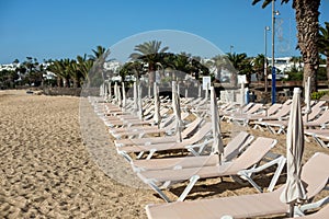 Empty chaise-lounges on the beach in the city of Costa Teguise