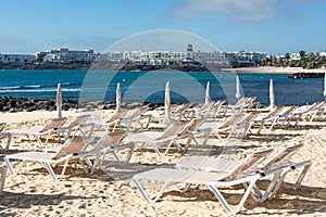 Empty chaise-lounges on the beach in the city of Costa Teguise