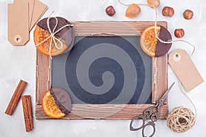 Empty chalkboard with candied sliced oranges, nuts, rope, scissors and empty label, sweet gifts, horizontal, copy space, top view