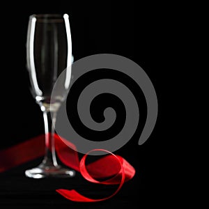 Empty champagne glass and red ribbon.