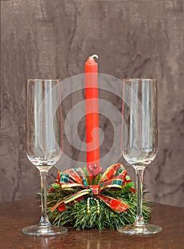 Empty champagne glasses on a background of red candles in a Christmas candlestick