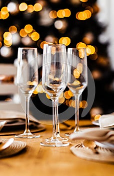 Empty champagne glasses stand on the festive table against the background of the Christmas tree