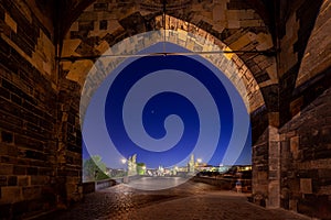 Empty Charles Bridge in the center of Prague during first wave of Covid-19 pandemy in the night with blue sky and yello