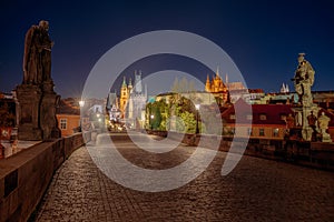 Empty Charles Bridge in the center of Prague during first wave of Covid-19 pandemy in the night with blue sky and yello