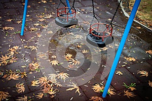 Empty children swing on a deserted playground in autumn after rain
