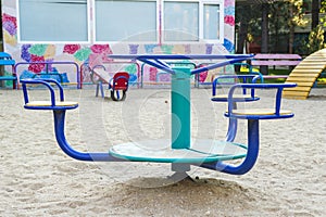 Empty childrens metal carousel on outdoor playground. Concept of entertaining street leisure for children, improvement of the