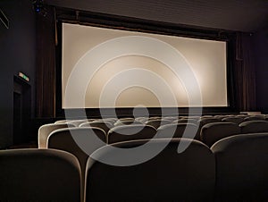 Empty cinema room with white kinescope (screen) and armchairs