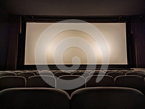 Empty cinema room with white kinescope (screen) and armchairs