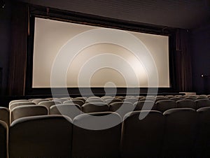 Empty cinema room with white kinescope (screen) and armchairs