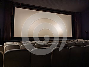 Empty cinema room with white kinescope (screen) and armchairs photo