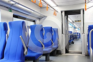empty city subway car. empty blue chairs in the electric train carriage and orange handrails